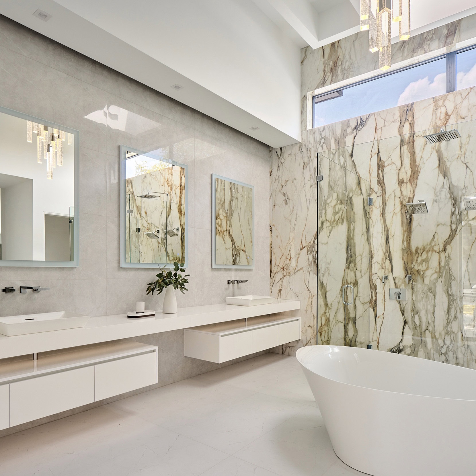Organic luxury bath suite with floating matte white vanities and expressive marble in The Dominion home
