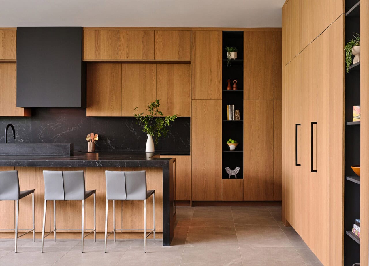 Bespoke kitchen cabinetry with wood panels and island seating in The Dominion, San Antonio